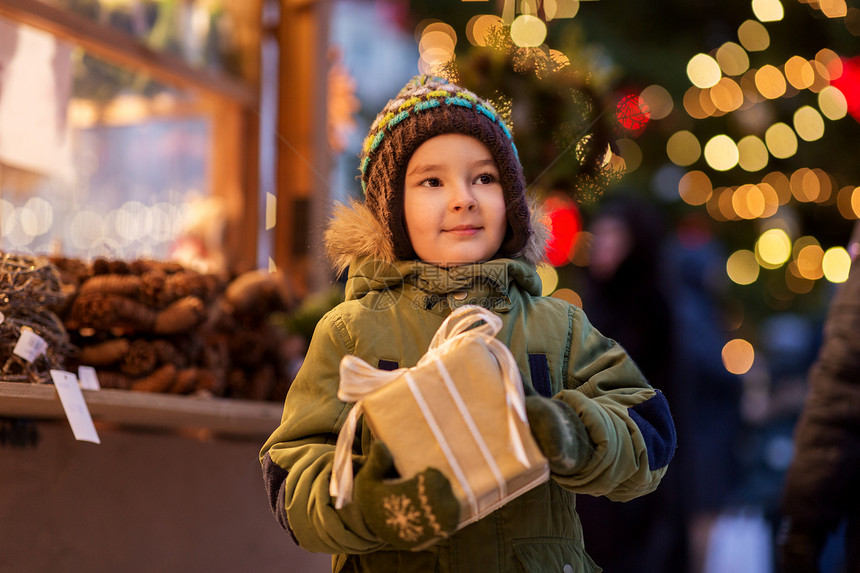 假期,童人的快乐的小男孩与礼品盒诞市场冬季晚上诞市场上带礼品盒的快乐男孩图片