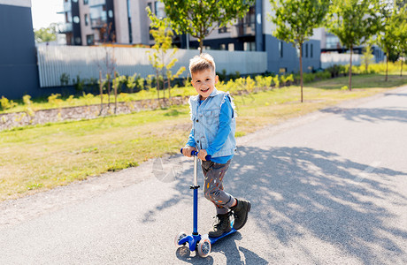 童,休闲趣的快乐的小男孩骑滑板车城市快乐的小男孩城市里骑滑板车背景图片