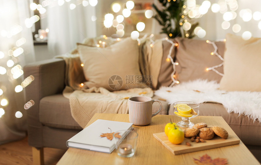 潮湿舒适的家庭杯柠檬茶,书,秋叶燕麦饼干木制桌子客厅家里桌子上柠檬茶书饼干图片