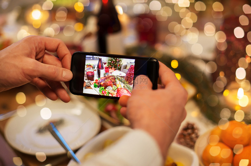食物技术假日诞节晚餐时,用智能手机拍摄烤火鸡诞节晚餐时双手拍照食物图片