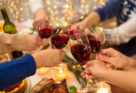 节日庆祝亲密的朋友家里吃诞晚餐,喝红酒碰杯亲密的朋友用葡萄酒庆祝诞节背景图片
