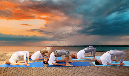 捣练图健身,运动,瑜伽健康的生活方式群人日落背景下的海上码头上桥式群人户外瑜伽练背景