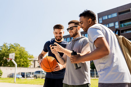 户外篮球操场篮球操场上用智能手机的男人背景图片