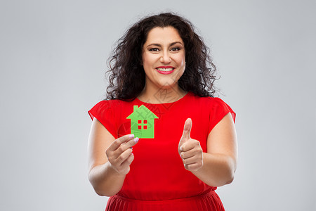 女人拿着绿色房子图标并竖大拇指图片