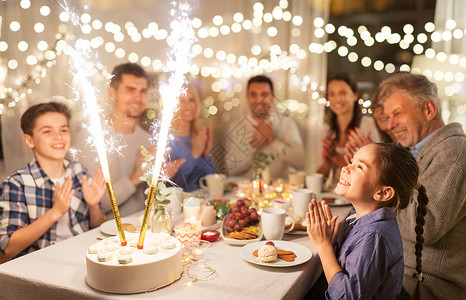 快乐的家庭举行晚餐聚会,喷泉烟花火花蜡烛燃烧蛋糕图片