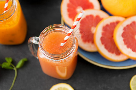 柑橘类水果石板桌梅森罐杯果汁与纸吸管图片