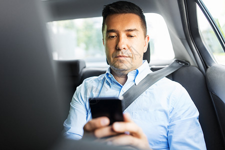 运输商业通信出租车后座用智能手机的男乘客商人乘客商人汽车中用智能手机图片