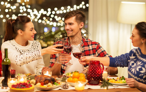 节日庆祝快乐的朋友家里吃诞晚餐,喝红酒碰杯快乐的朋友诞节聚会上喝红酒图片