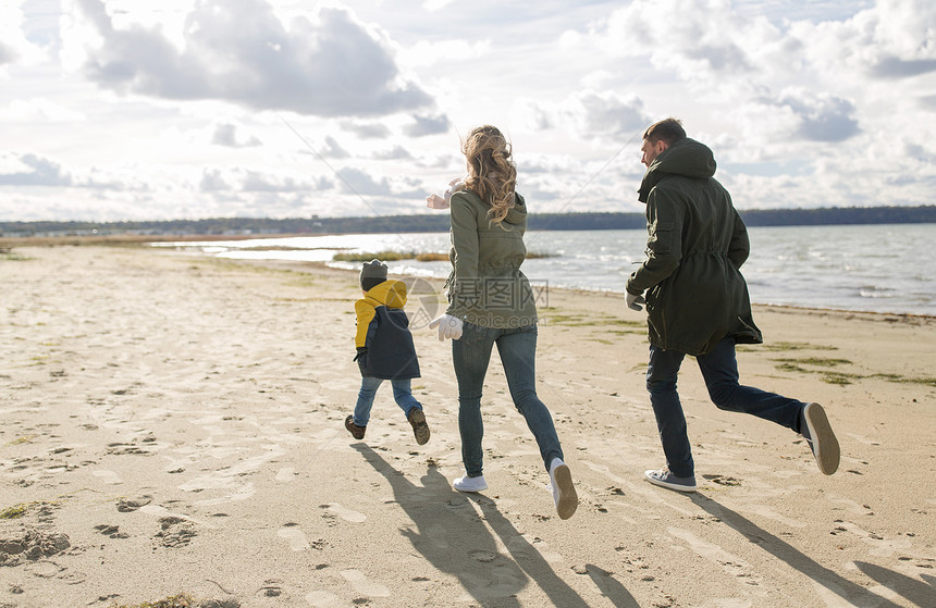 家庭,休闲人的快乐的母亲,父亲小儿子沿着秋天的海滩跑步幸福的家庭沿着秋天的海滩奔跑图片