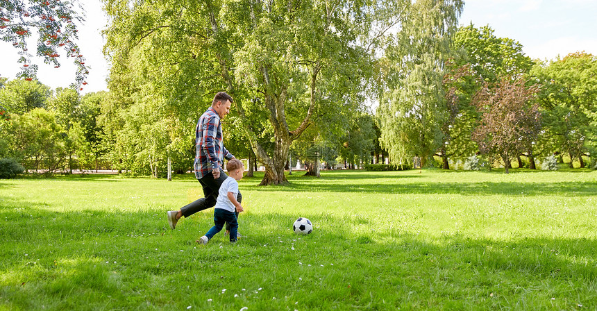 家庭休闲人的快乐的父亲小儿子夏天的公园踢足球快乐的父子夏天的公园踢足球图片