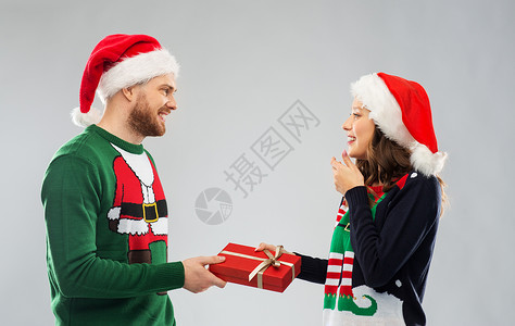 人节日的幸福的夫妇戴着诞帽,毛衣派上诞礼物诞毛衣礼品盒的幸福夫妇图片
