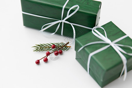 寒假,新诞节的礼品盒包装成绿色的纸杉木树枝与红色浆果白色的背景绿色礼品盒带浆果的冷杉树枝背景图片