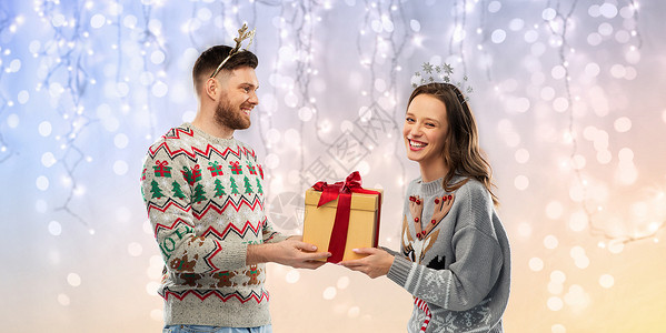 人节日的幸福夫妇的肖像与诞礼物毛衣节日灯背景幸福的夫妇穿着毛衣诞礼物图片