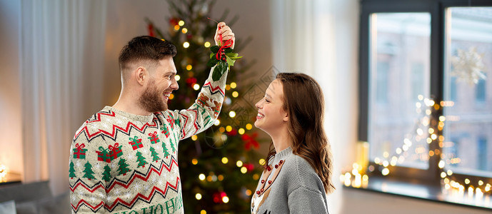 诞节,人们节日传统的幸福的夫妇毛衣与槲寄生家里的背景诞快乐的夫妇槲寄生家里背景