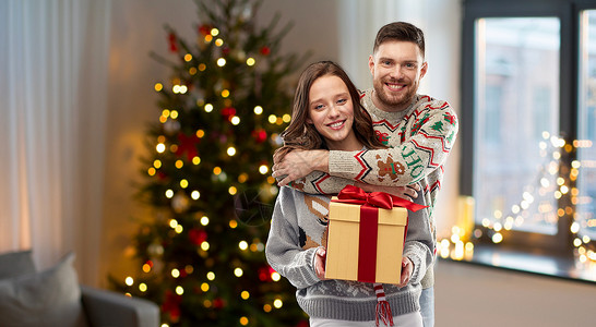 人节日的幸福夫妇的肖像与诞礼物毛衣家庭背景诞毛衣礼品盒的幸福夫妇背景图片
