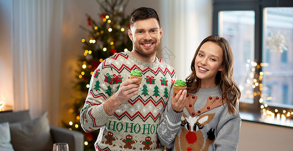 毛衣图案诞节,人假日的幸福的夫妇毛衣派与纸杯蛋糕家庭背景夫妇带着纸杯蛋糕穿着诞毛衣背景