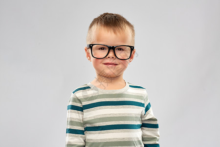 学校,教育视觉微笑的小男孩灰色背景小男孩的肖像戴眼镜微笑的小男孩的肖像图片