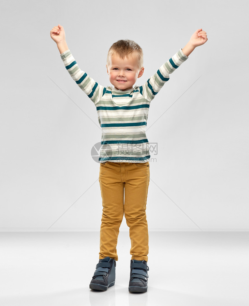 童,成功人的快乐的小男孩穿着条纹衬衫,举手灰色背景上快乐的小男孩举了手图片