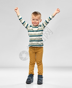 童,成功人的快乐的小男孩穿着条纹衬衫,举手灰色背景上快乐的小男孩举了手图片