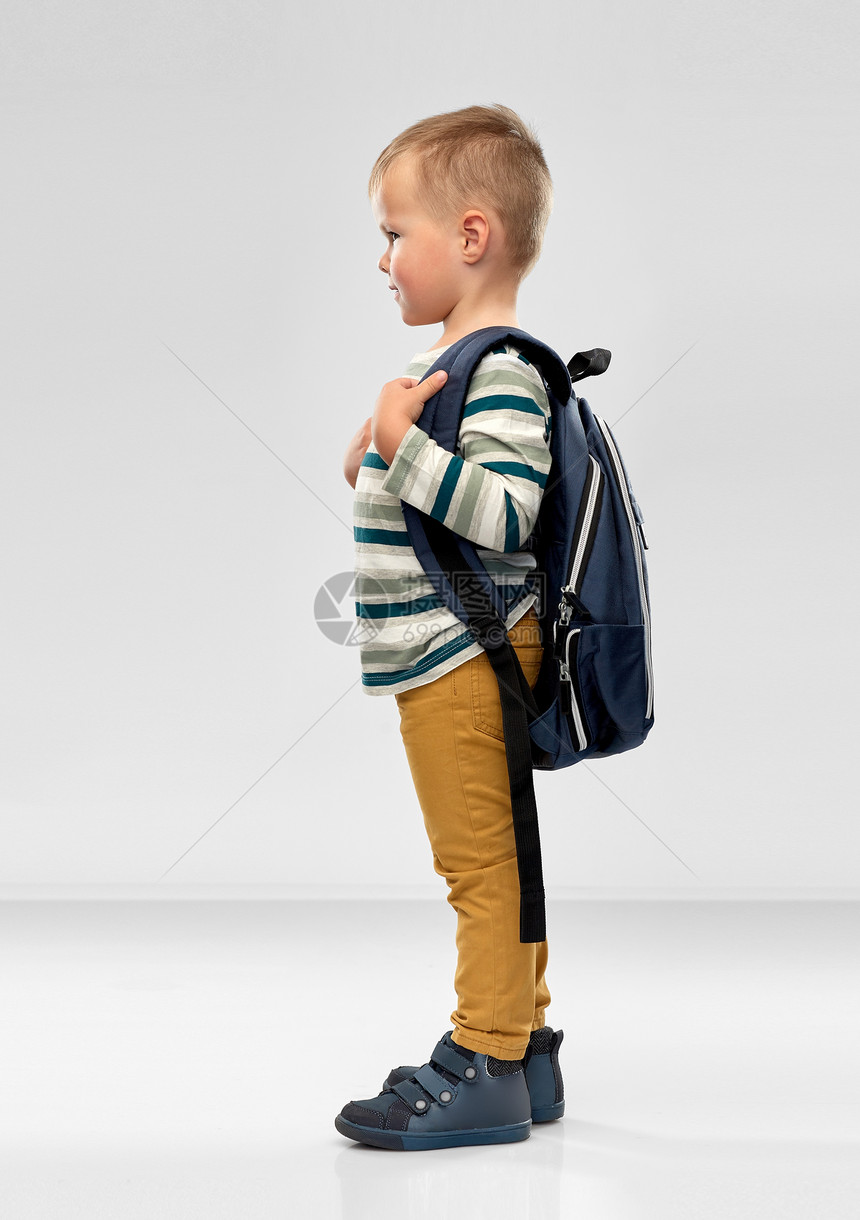 学前教育儿童微笑的小男孩与学校背包灰色背景的肖像带着学校背包的微笑男孩的肖像图片
