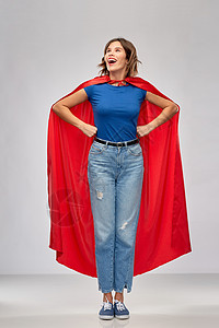 女人的力量人的快乐的女人红色超级英雄披风灰色背景穿着红色超级英雄斗篷的快乐女人背景图片