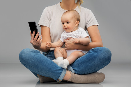家庭技术母母亲婴儿看智能手机母亲婴儿看着智能手机图片