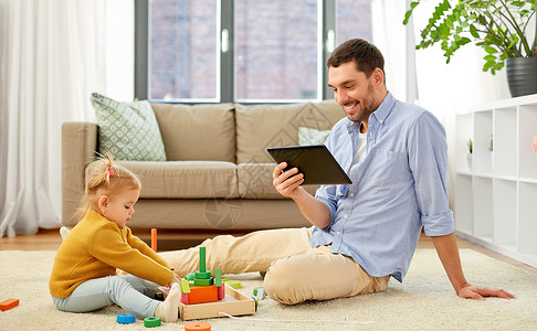父亲与孩子玩家庭,父亲人的快乐的父亲与平板电脑电脑小女儿玩木制玩具积木套件家里父亲平板电脑婴儿女儿家背景