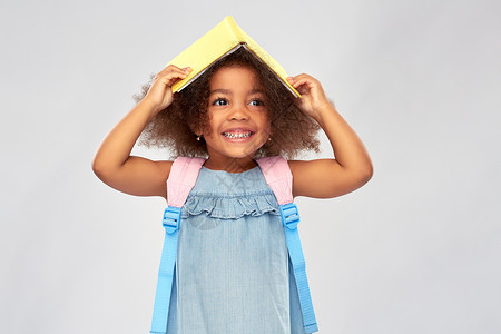 与众不童童,学校教育快乐的非裔美国女孩与书籍背包灰色背景带着书背包的快乐的非洲小女孩背景