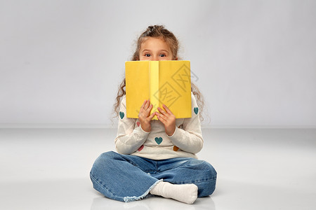 阅读,教育童的小女孩坐地板上,带着灰色背景的书小女孩坐地板上着书图片
