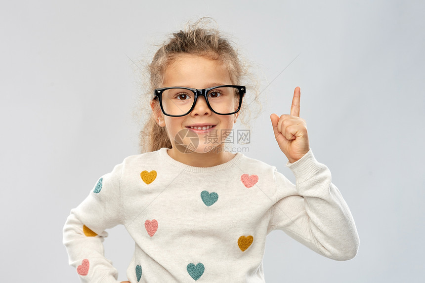 学校,教育视觉微笑的小女孩戴着眼镜,手指指向灰色背景戴眼镜的女孩的肖像指向手指图片