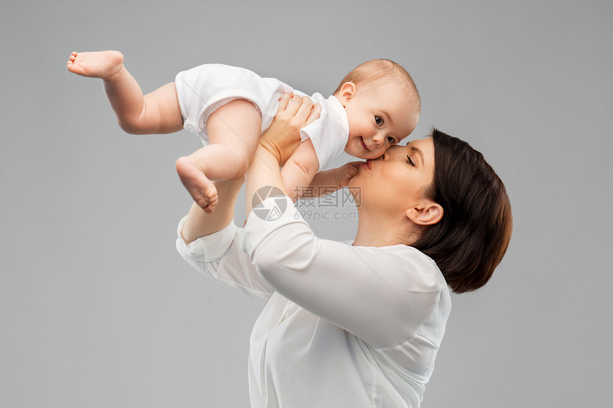 家庭,孩子父母的快乐的微笑中母亲亲吻小婴儿的女儿灰色的背景快乐的母亲亲吻小宝贝女儿图片