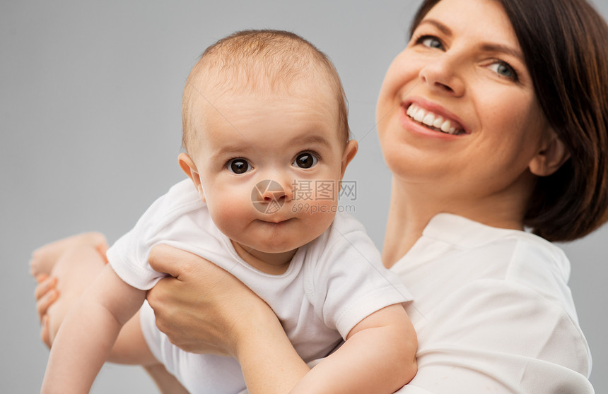 家庭孩子父母的快乐的微笑中母亲抱着灰色背景的小女儿快乐的中母亲小女儿图片