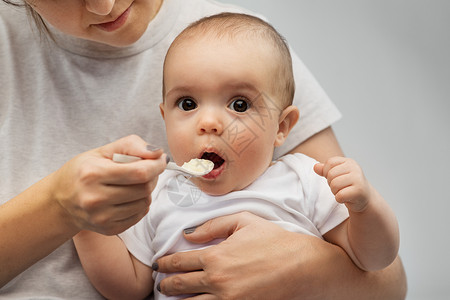孩子,吃食物的密切母亲用勺子喂养小婴儿用勺子喂小宝宝来亲近妈妈图片