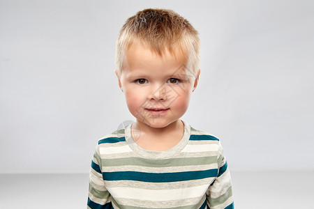 童人们的灰色背景上穿条纹衬衫的小男孩的肖像穿条纹衬衫的小男孩的肖像图片