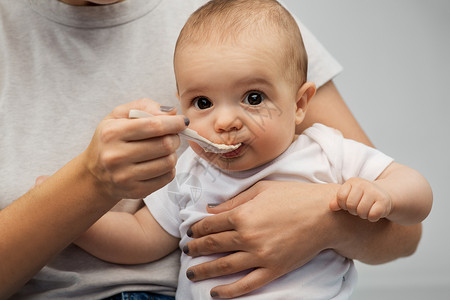 勺式进料孩子,吃食物的密切母亲用勺子喂养小婴儿用勺子喂小宝宝来亲近妈妈背景