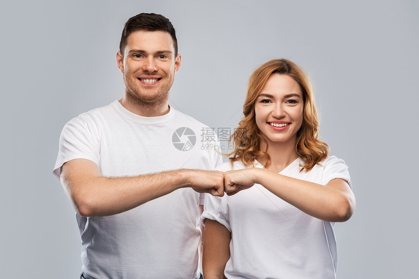 关系,友谊人的幸福的夫妇白色t恤上拳头碰撞手势灰色背景上的肖像穿着白色T恤的幸福夫妇的肖像图片