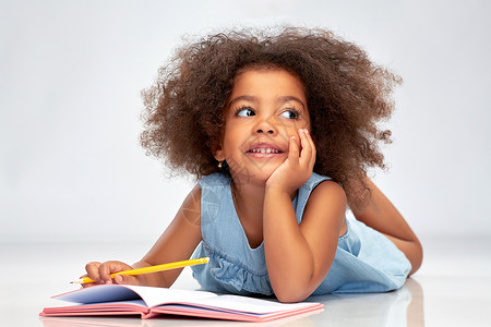 童,创造力,绘画人的快乐的非裔美国女孩与素描本铅笔灰色背景快乐的非裔美国女孩与素描本背景图片