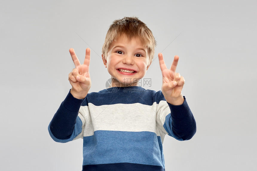 童,手势人的微笑的小男孩条纹套衫平手标志灰色背景穿条纹套衫的小男孩表现出平静图片