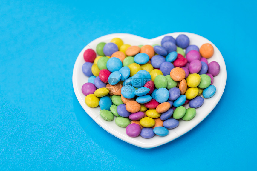 糖果,糖果情人节糖果滴心形盘子上的蓝色背景蓝色背景上心形盘子上的糖果图片