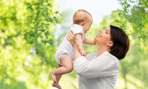 家庭,孩子父母的快乐的微笑中母亲抱着小宝贝女儿绿色的自然背景快乐的中母亲小女儿图片