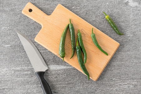 蔬菜,食物烹饪绿色辣椒菜刀木制切割板石板石背景绿色辣椒切板上的刀图片
