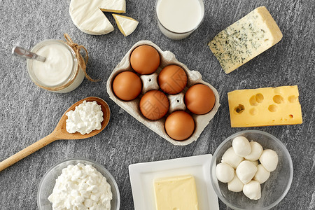 各种各样的开销食物饮食干酪,牛奶瓶,自制酸奶与黄油鸡蛋石桌上牛奶,酸奶,鸡蛋,干酪黄油背景