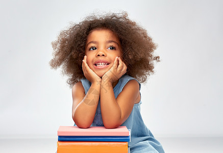 非洲孩子微笑小非裔美国女孩与书籍背景