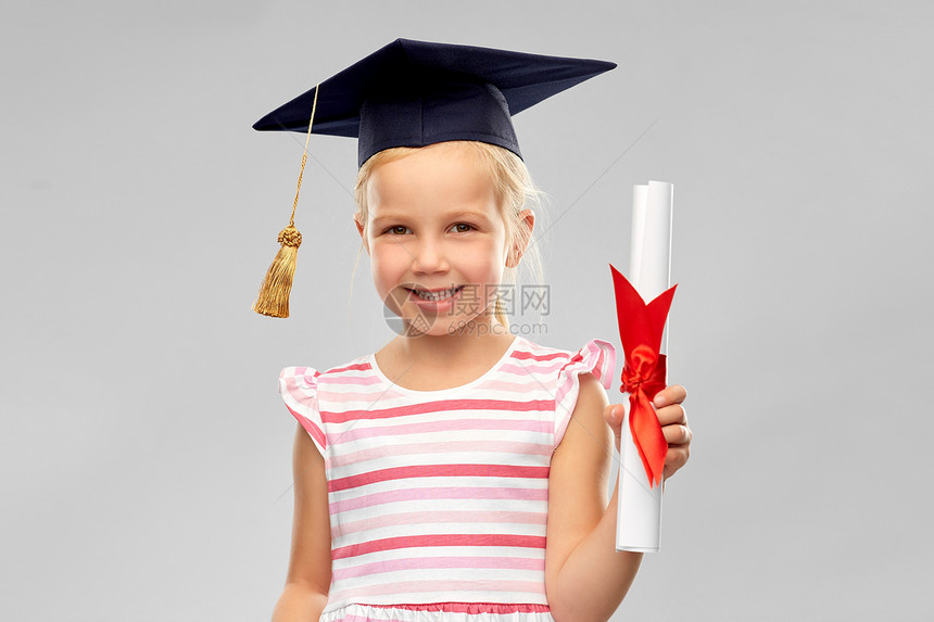 学校,教育学快乐的小女孩戴着学士帽灰背景文凭的黑板文凭的灰泥板上的小女孩图片