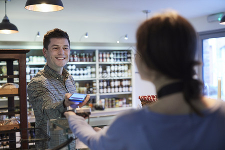 男客户熟食店用手机进行非接触式支付购物高清图片