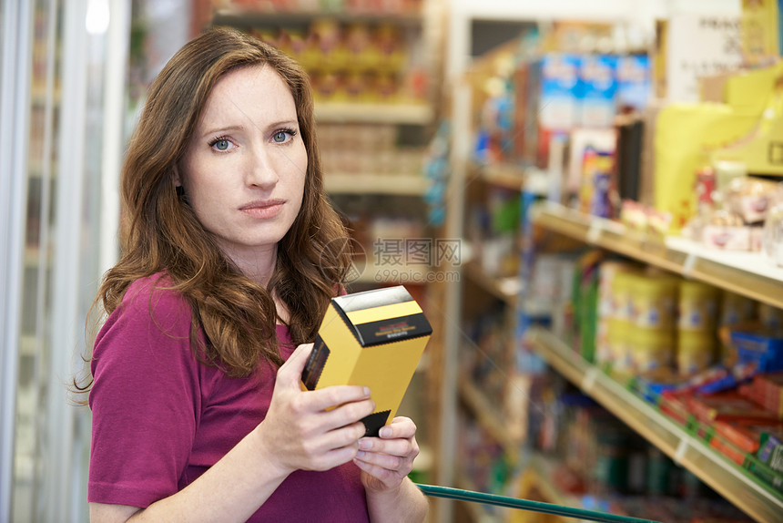 超市的盒子上检查食物标签的女人的肖像图片