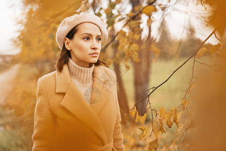 户外时尚照片,轻美丽的女士穿着米色外套,针毛衣贝雷帽包围秋叶温暖的秋天图片