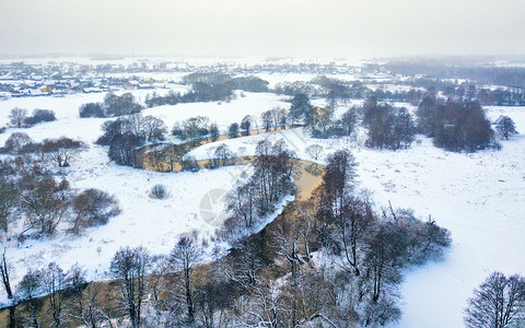 冬季雪河的鸟瞰图白俄罗斯明斯克附近的河岸草地上的冷冻树木背景上的村庄图片