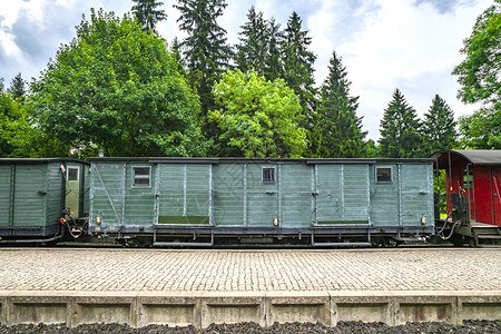 多云天气的背景下,火车车厢铁路上,车站绿树图片