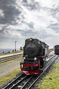黑色火车头,红色驾驶多云的天空下的跑道上图片